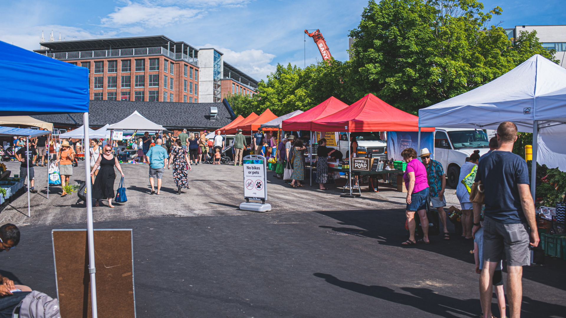 Market stalls set-up under tents and customers shopping.